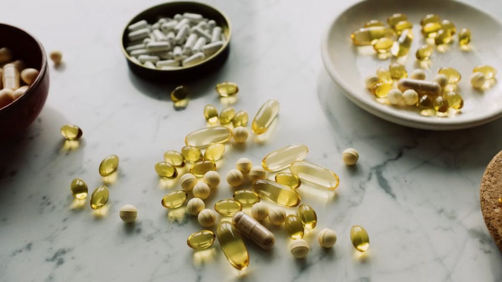 Close-up of various pills and capsules scattered on a marble surface, symbolizing healthcare and medicine.