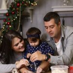 A joyful family of three baking together in a festive kitchen setting.