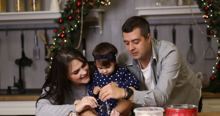A joyful family of three baking together in a festive kitchen setting.